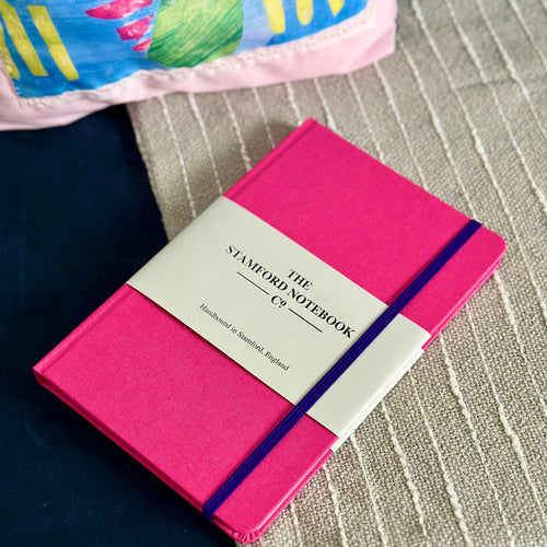 Hot Pink notebook with purple trim. Hnad bound with our own British made paper. Can be personalised.